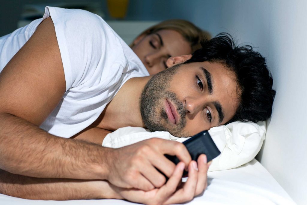 Man using iPhone in bed